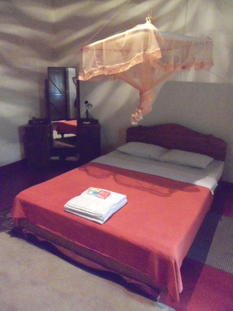 Old but comfortable bed, with mosquito net, in Sunnyside Holiday Bungalow