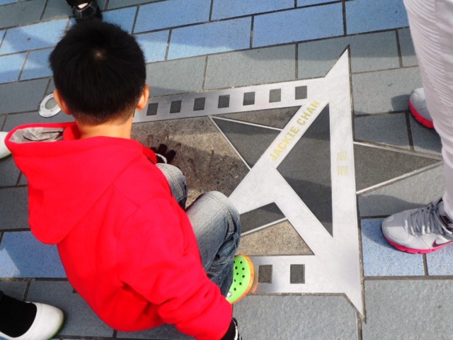 A kid with Jackie Chan's plaque at Avenue of Stars