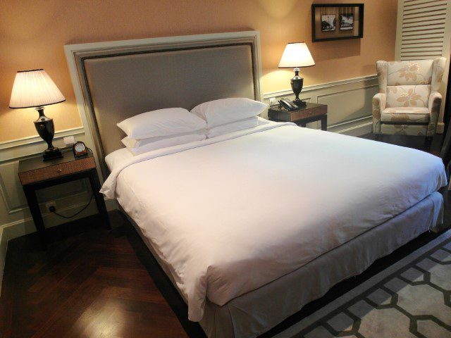 Bed and armchair of the Eastern and Oriental Hotel Studio Suite