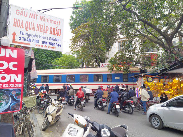 Touting by railway cafe owners in Hanoi along railway track (extreme right people standing next to track)