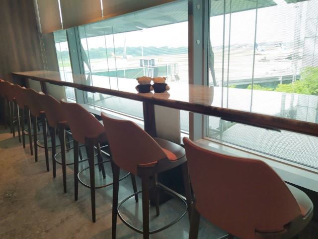 Lounge seats at entrance of Business Class SilverKris Lounge with views of the runways at Changi Airport